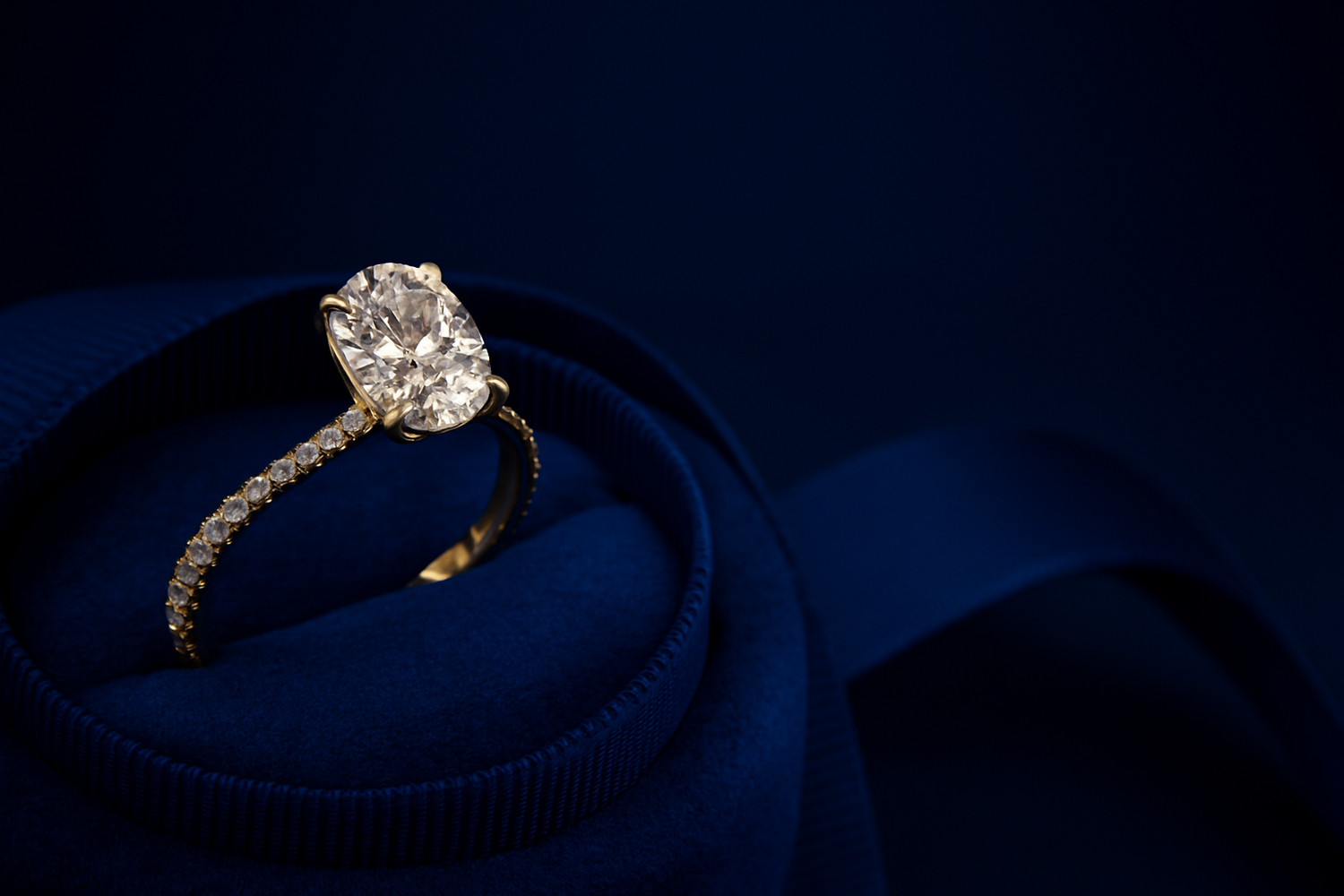 Diamond ring on a blue cushion against a dark background